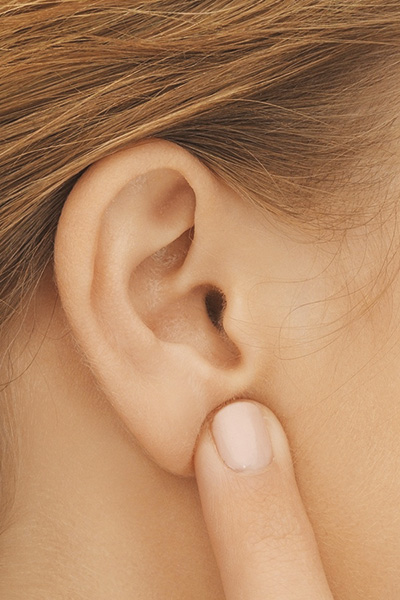 Begleitfoto: Frau zeigt auf ihr Ohr